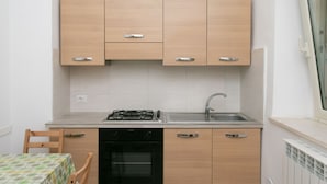 A compact kitchen with a gas stove, oven, sink, and wooden cabinets. - N151 - Numana, delightful two-room apartment with porch (Numana)