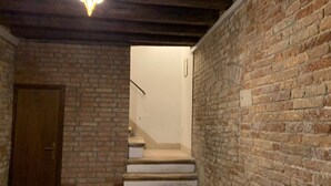 A staircase leading to a room with a brick wall and a wooden door. - Grimaldi Apartments - Casa di Emma (Venice)
