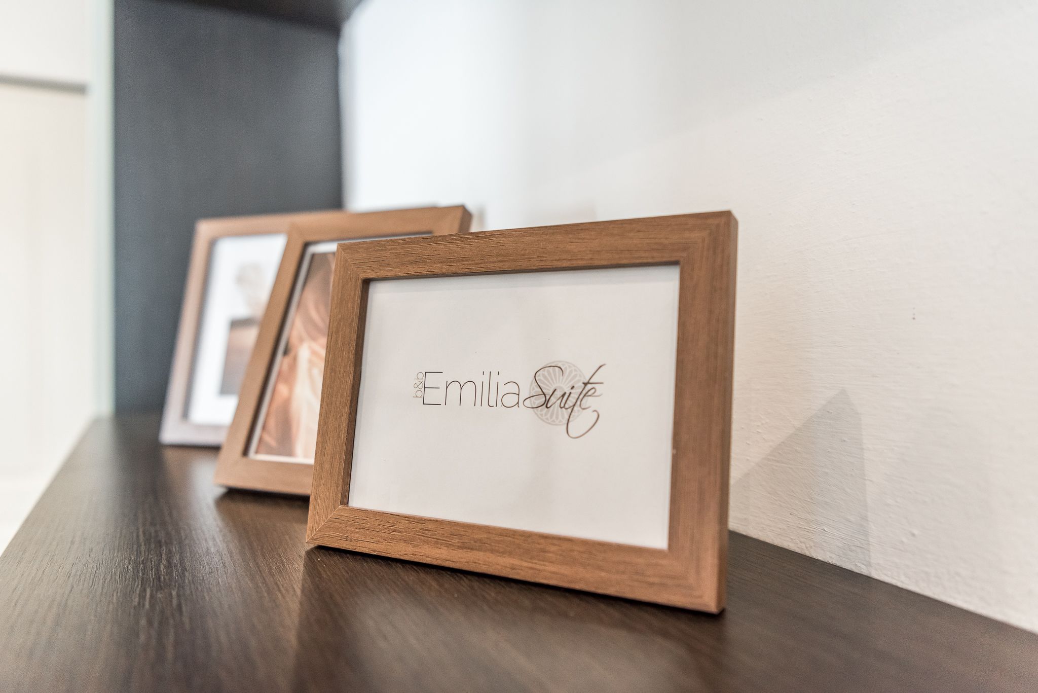 Una fotografía con marco de madera que muestra el nombre "Emilia Suite" sobre una superficie de madera oscura.