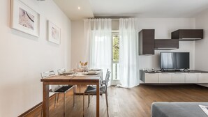 A modern kitchen with a dining area, a TV, and a window with curtains. - Emilia Suite Life (Modena)