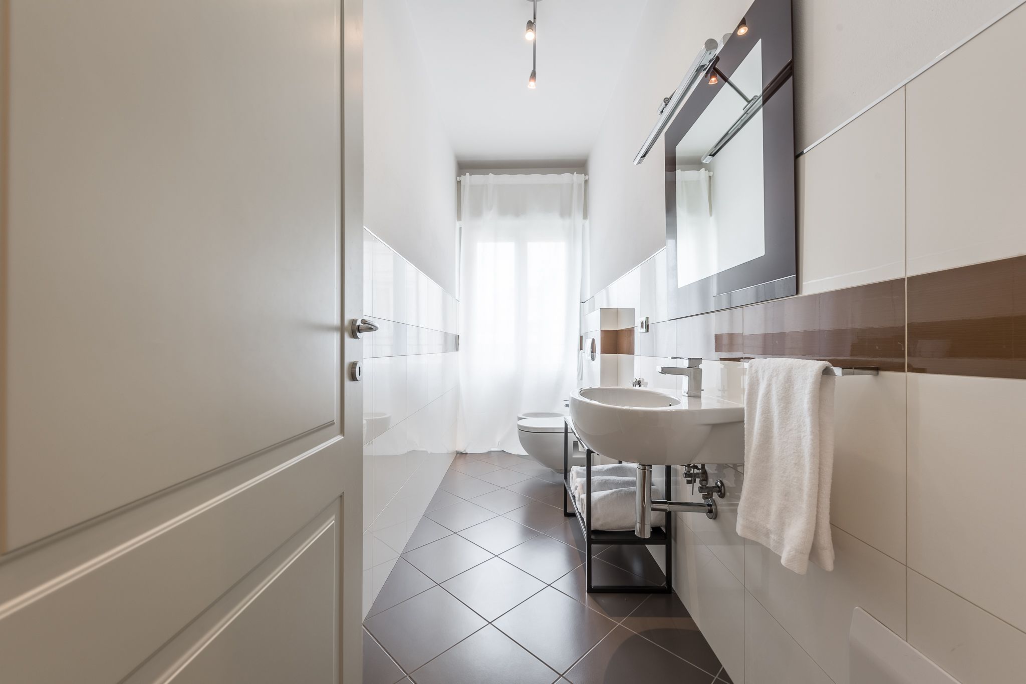 Un baño moderno con un lavabo, espejo y retrete blancos.