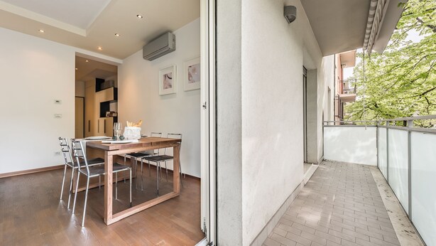 A modern apartment with a dining area, a balcony, and a view of greenery. - Emilia Suite Life (Modena)