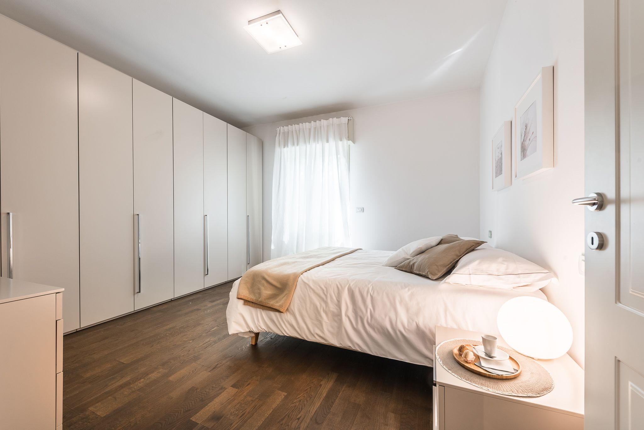 A bedroom with a bed, bedside table, and a nightstand with a lamp.
