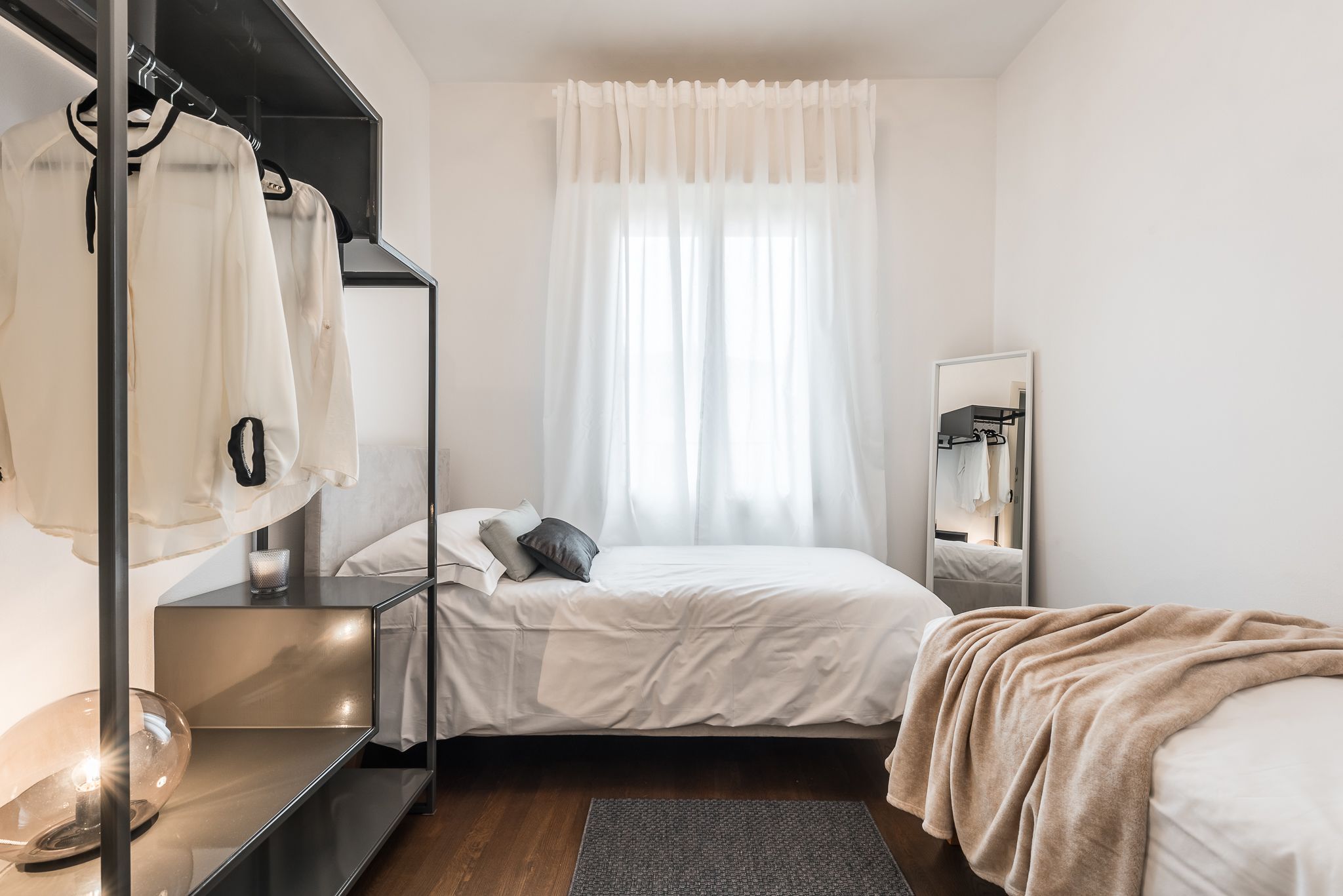 A bedroom with a bed, a bedside table, a mirror, and a wardrobe.