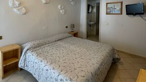 A bedroom with a bed, a nightstand, a wall-mounted TV, and a ceiling light.