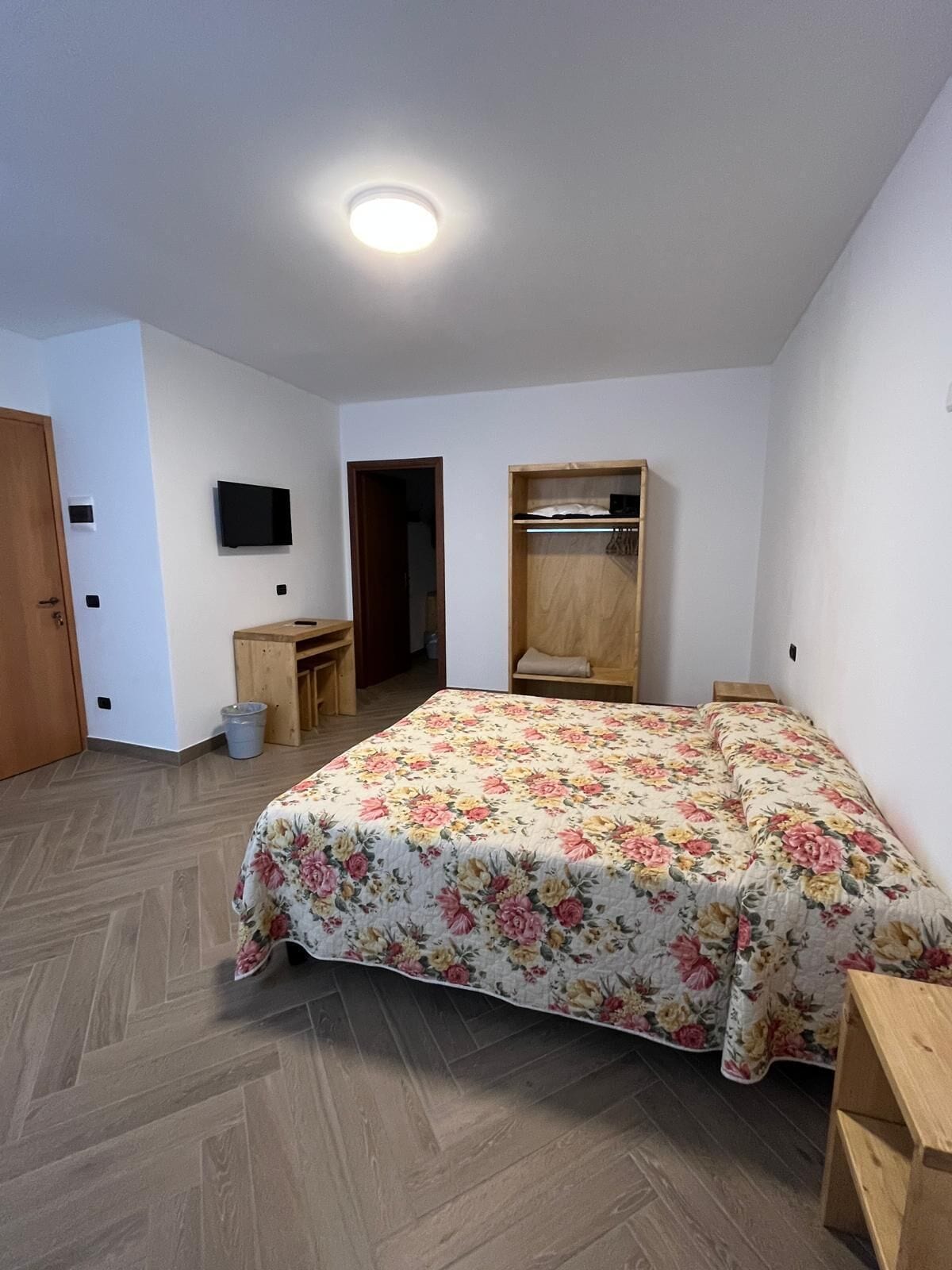 A bedroom with a bed, a desk, a TV, and a wardrobe.