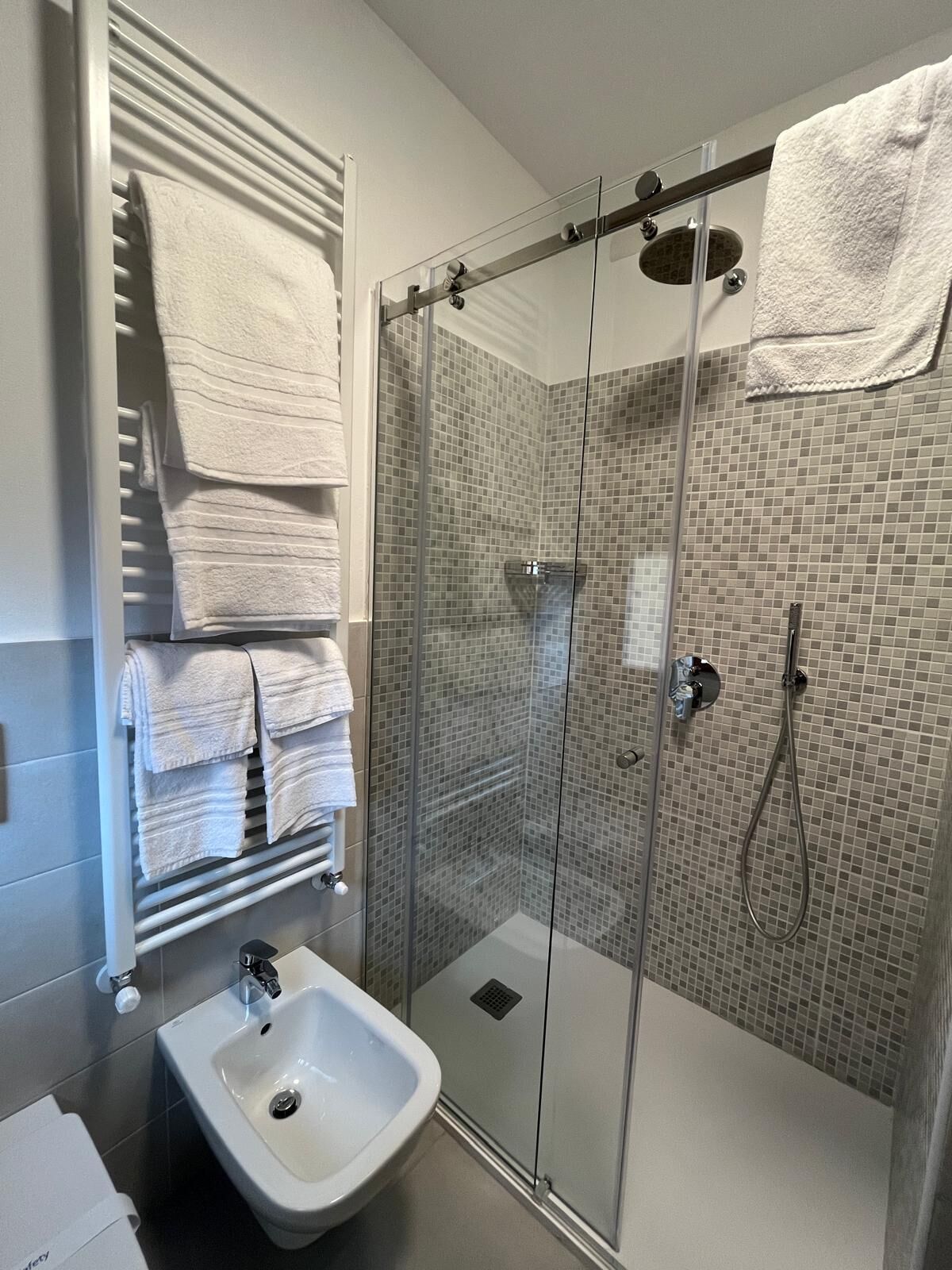 A modern bathroom with a glass-enclosed shower, a white sink, and a towel rack with folded towels.