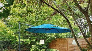 A wooden deck with a picnic table and a blue umbrella. - Le Colombard, cosy B&B (CONDOM)