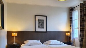 A neatly arranged hotel room with a double bed, two bedside tables with lamps, a framed picture on the wall, and a window with curtains. - Le Colombard, cosy B&B (CONDOM)