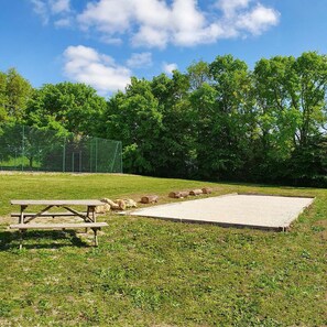 A picnic area with a table and benches, surrounded by a grassy field and trees.