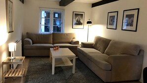 A living room with a sofa, a coffee table, a lamp, and framed pictures on the wall. - Schönes Ferienhaus in Strandnähe (Rødekro)
