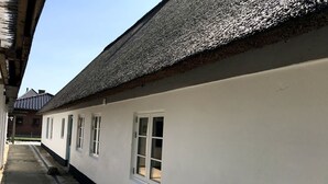 A row of white buildings with thatched roofs and a cobblestone path. - Schönes Ferienhaus in Strandnähe (Rødekro)