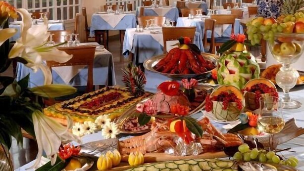 Zona pranzo con diversi tavoli apparecchiati per un pasto, con una varietà di cibi e bevande.