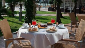Un'area pranzo all'aperto con un tavolo apparecchiato per la colazione, inclusi pane, frutta e bevande.