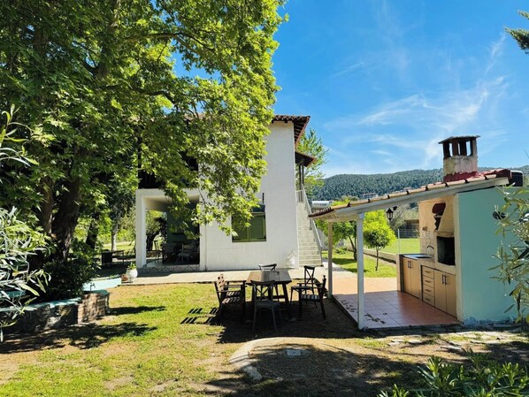Una casa moderna con un patio, mobiliario exterior y vistas del paisaje circundante.