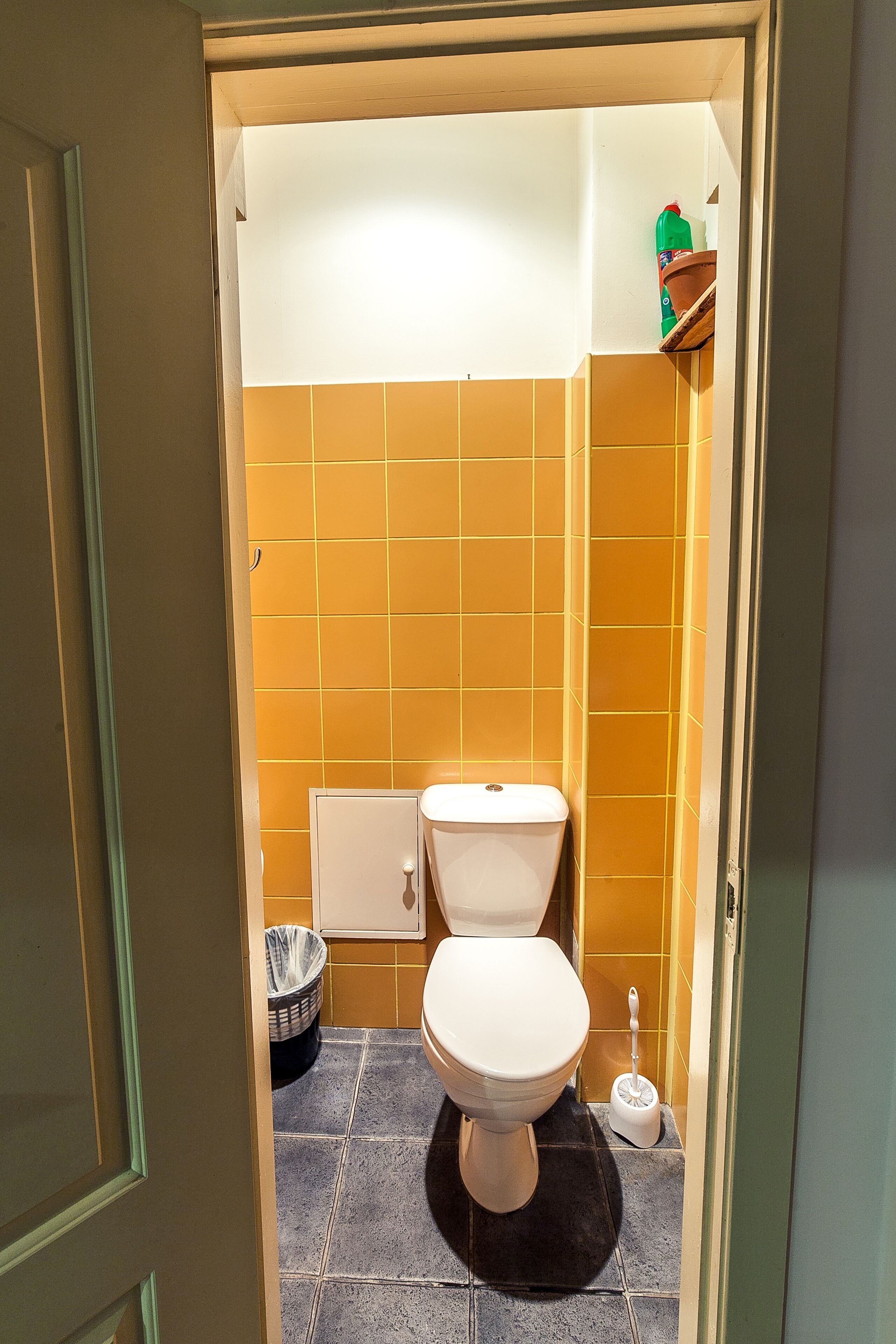Un baño pequeño con inodoro, un cesto de basura y un escobillón.