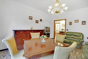 Un comedor con mesa de madera, sillas, una lámpara de araña y cuadros en la pared.