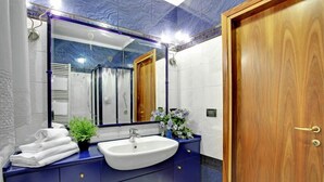 A bathroom with a large mirror, a sink, and a wooden door. - Grimaldi Apartments - Elena (Venice)