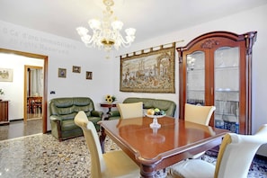 A dining area with a wooden table, green leather sofas, and a chandelier. - Grimaldi Apartments - Elena (Venice)