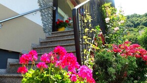Un edificio moderno con fachada de piedra, una escalera de metal y un balcón con plantas en macetas.