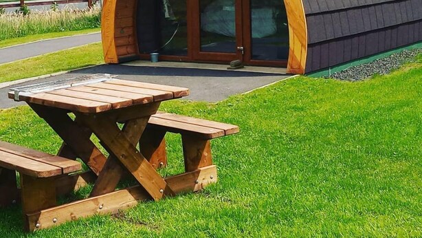 A small, semi-open structure with a curved roof and a wooden bench in front. - Standing Stones Lodge (Belfast)