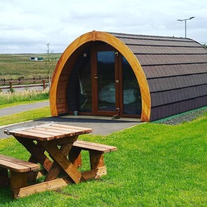 A small, semi-open structure with a curved roof and a wooden bench in front. - Standing Stones Lodge (Belfast)