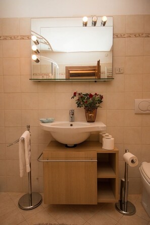A bathroom with a vanity, sink, mirror, and a small potted plant.