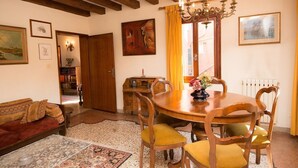 A dining area with a wooden table and chairs, a chandelier, and a painting on the wall. - Grimaldi Apartments - San Marco Economy (Venice)