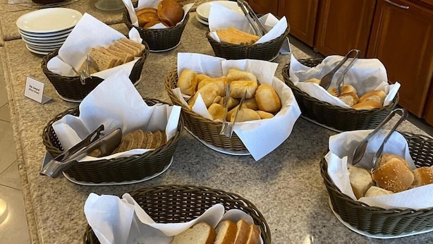 Un buffet proposant une variété de pains, de viennoiseries et de fruits.
