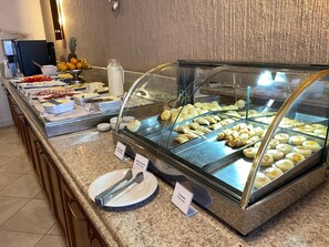 Buffet amb diverses opcions gastronòmiques, incloent pastissos, fruita i condiments.