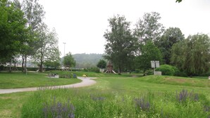 Ein Park mit einem Spielplatz, einer kleinen Holzkonstruktion und einem gewundenen Weg.