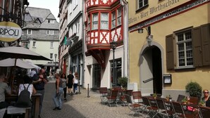 Eine Kopfsteinpflasterstraße mit Außenbereich, ein traditionelles Gebäude mit roter und weißer Fassade und ein Schild für eine Bar.
