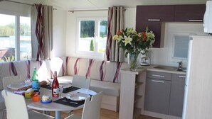 A compact kitchen with a sink, a small dining area with a table and chairs, and a sofa. - Camping Pen Guen (Saint-Cast-le-Guildo)