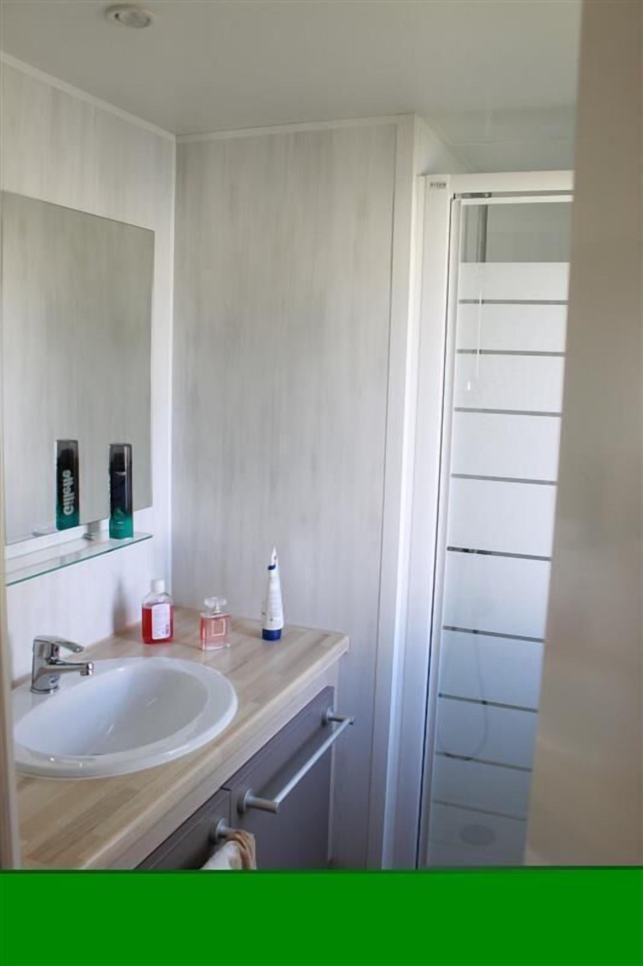Un baño moderno con un espejo grande, un lavamanos y una zona de ducha.