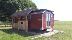 A small red wooden structure with a sloped roof, a wooden fence, and a 'FOLLOW ME' sign.