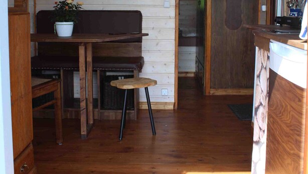 A wooden interior with a bench, table, and a door leading to another room.