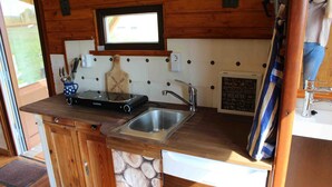 A compact kitchen with wooden cabinets, a built-in sink, and a window above the countertop.