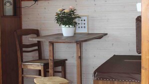 A wooden interior with a table, chairs, a potted plant, a television, and a radio.