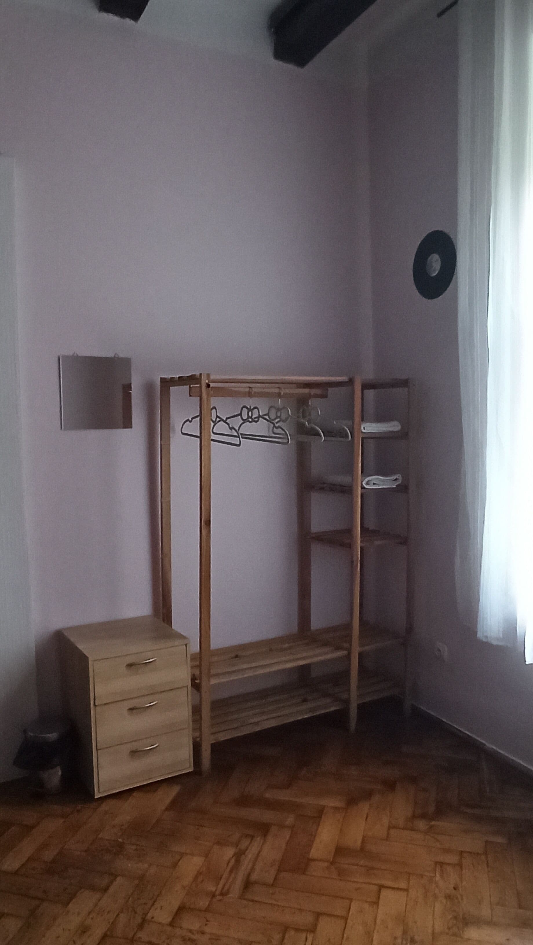 A room with a wooden bunk bed, a small dresser, and a wall-mounted shelf.