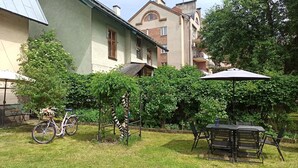 Un patio con una mesa, sillas, una bicicleta y una pérgola con plantas trepadoras.