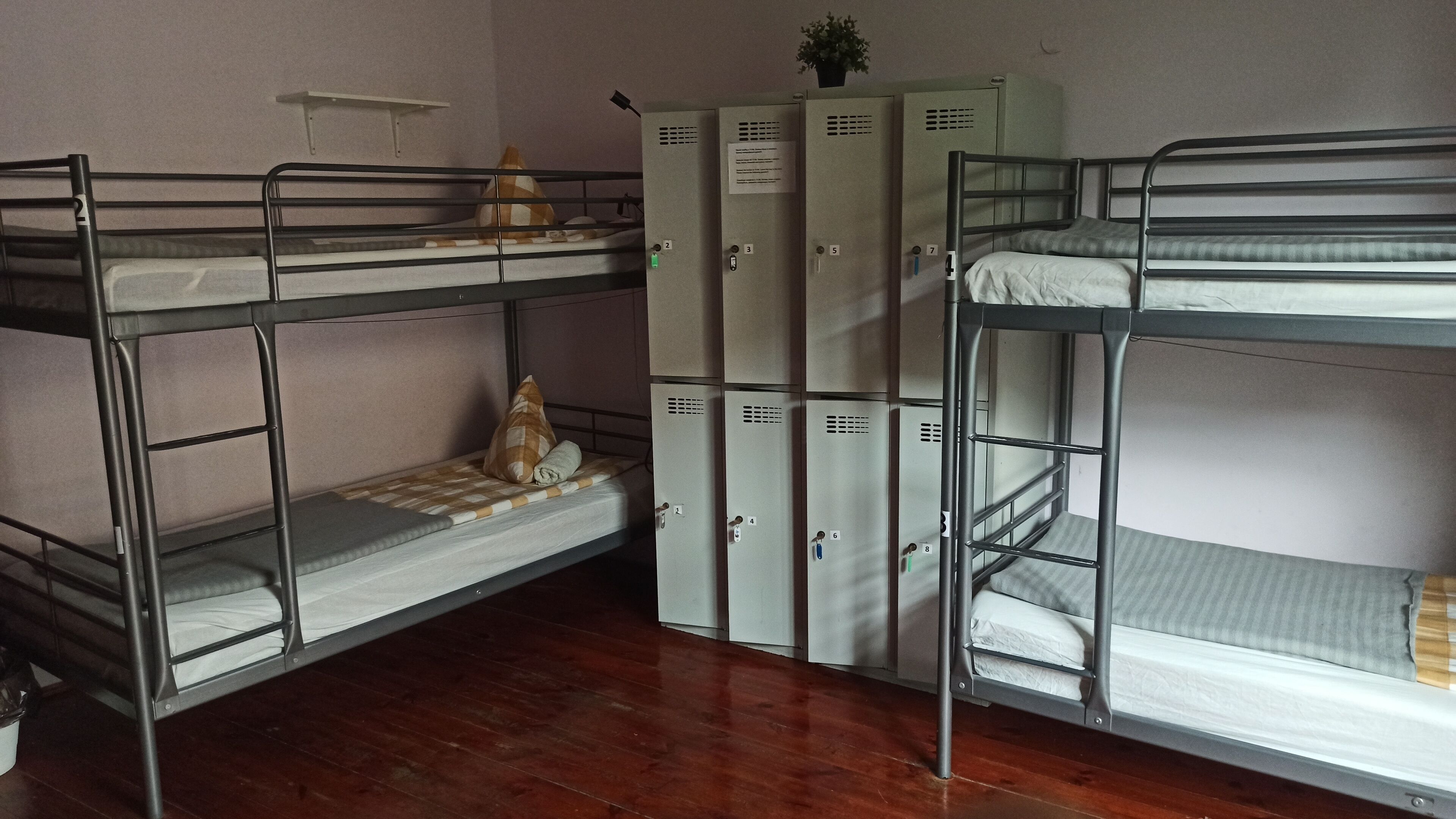 Une chambre de dortoir avec des lits superposés, une petite étagère et une rangée de casiers.