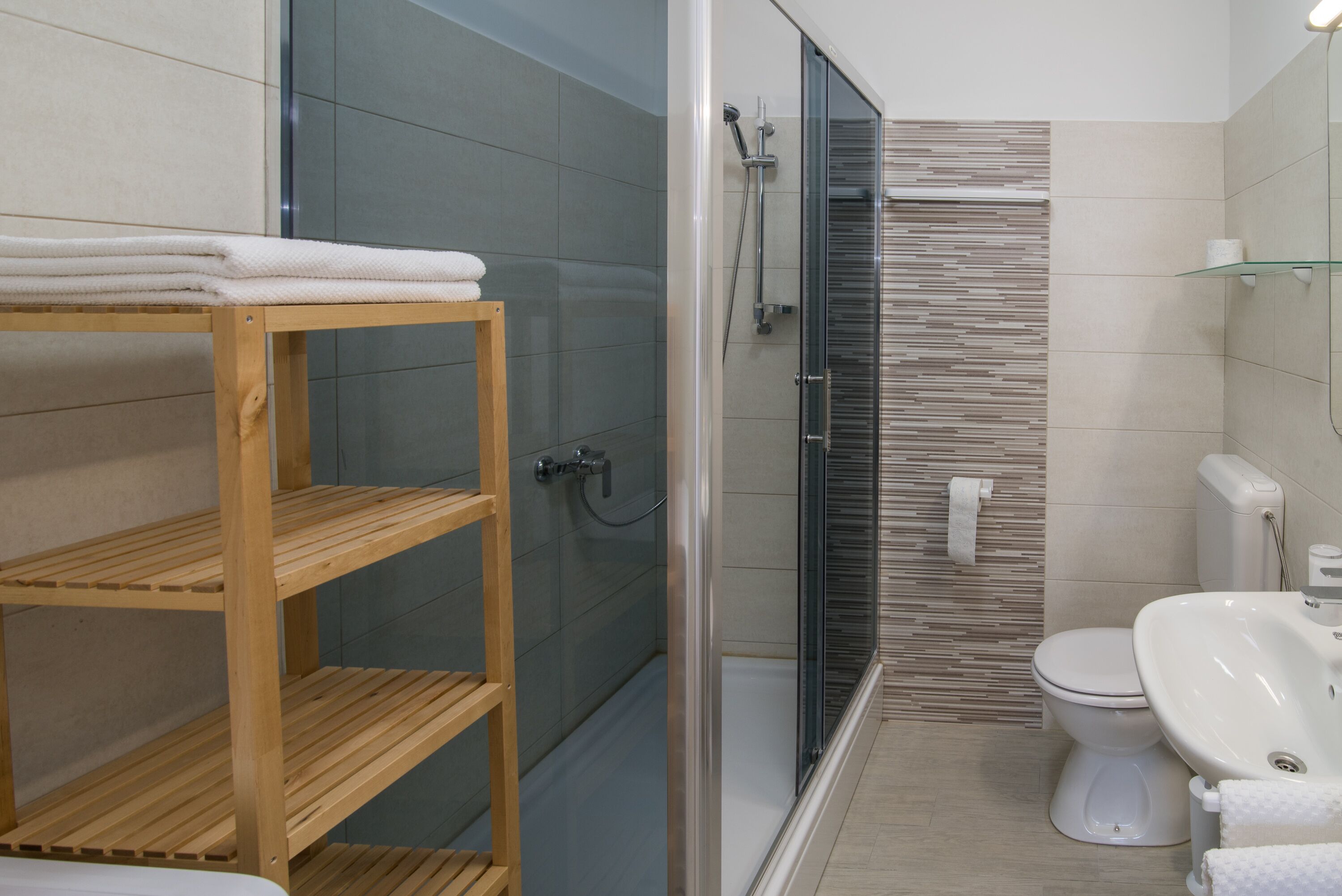 A modern bathroom with a glass shower enclosure, a toilet, and a sink.