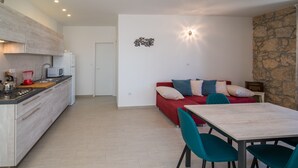 A modern kitchen with a red sofa and teal chairs in a living area. - Apartment for 4 person (Vrbnik)