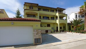A two-story building with a yellow facade, a stone fireplace, and a covered outdoor area with potted plants. - Holiday Apartment Near the Beach for 4 Persons With one Bedroom (Medulin)