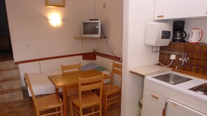 A compact kitchen with a dining table, chairs, a microwave, a coffee maker, and a sink. - Holiday Apartment Near the Beach for 4 Persons With one Bedroom (Medulin)