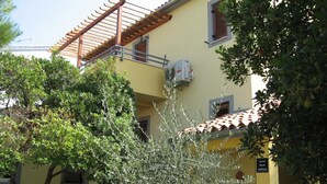A yellow building with a tiled roof, an air conditioning unit, and a sign indicating a restaurant. - Six Person Apartment With 2 Bedrooms Near the Beach in Pjescana Uvala (Medulin)