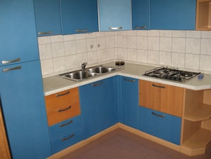 Kitchen area with double sink, gas stove, and countertop.