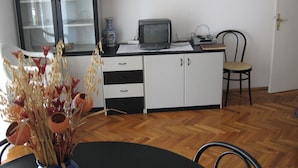 A room with a wooden herringbone floor, a dining table with chairs, a television on a cabinet, and a vase with dried plants. - Six Person Apartment With 2 Bedrooms Near the Beach in Pjescana Uvala (Medulin)