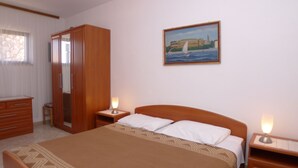 A bedroom with a bed, nightstands, a wardrobe, and a painting on the wall. - Apartment for two Persons With Swimming Pool Near the Beach (Medulin)