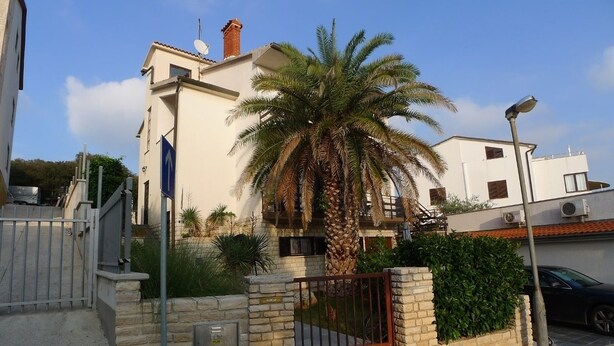 A gated residential area with a palm tree, a street lamp, and a parked car. - Apartment for two Persons With Swimming Pool Near the Beach (Medulin)